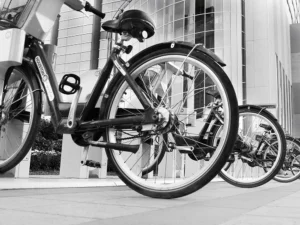 Urban bike station beside modern glass building, showcasing sustainable transit and architecture.