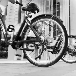 Urban bike station beside modern glass building, showcasing sustainable transit and architecture.