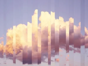 Soft clouds split into vertical fragments, revealing shifting layers of evening light.