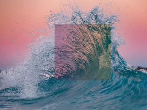 Ocean wave bursts under pink sky, refracted through a colorful square prism.