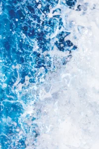 White frothy surf smashes and recoils back into cerulean waters.