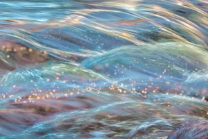 Sunlight sparkles along the surging iridescent waves.