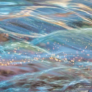 Sunlight sparkles along the surging iridescent waves.