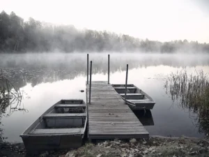 Misty morning stillness surrounds empty boats resting quietly beside the wooden dock.