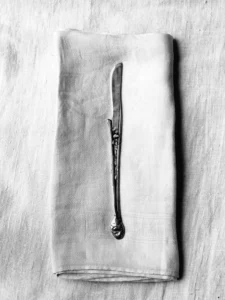 Elegant silver knife rests on folded linen, evoking timeless simplicity and quiet refinement.