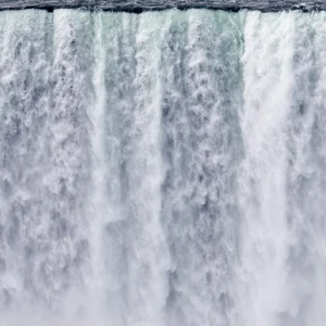Powerful cascade of rushing water crashes downward, capturing nature’s immense force and motion.