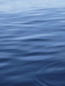 Gentle ripples glide smoothly, cool blue tones evoke peaceful ocean calm.