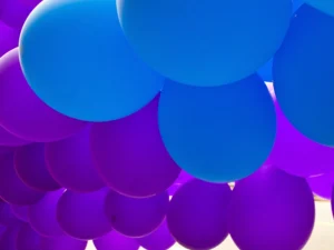 A sky of purple and blue floating balloons.