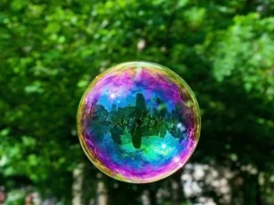 The artist can be seen in a crowd within the iridescent bubble, a moment suspended in time and space.