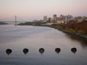 The Hudson river gleams along Riverside Park and the colorful autumn trees. The city nestled in the background, framed by George Washington Bridge.