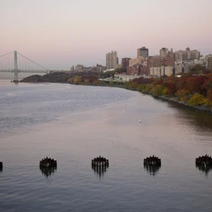The Hudson river gleams along Riverside Park and the colorful autumn trees. The city nestled in the background, framed by George Washington Bridge.